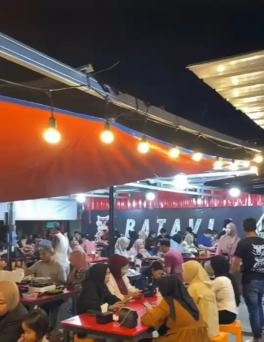 Pengunjung memenuhi meja merah di bawah lampu gantung pada malam hari