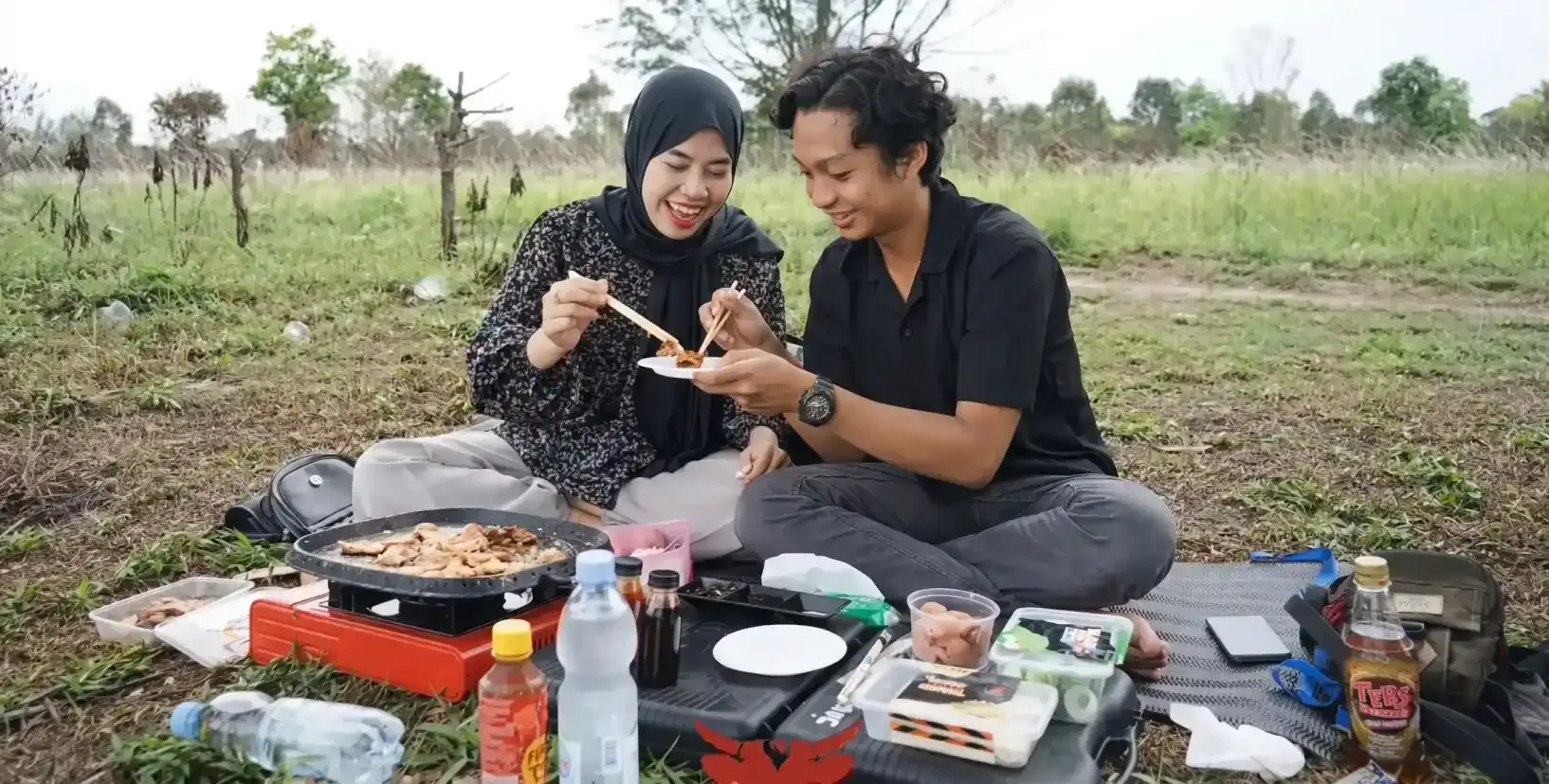 Pasangan nge-grill paket Home Service di lapangan rumput