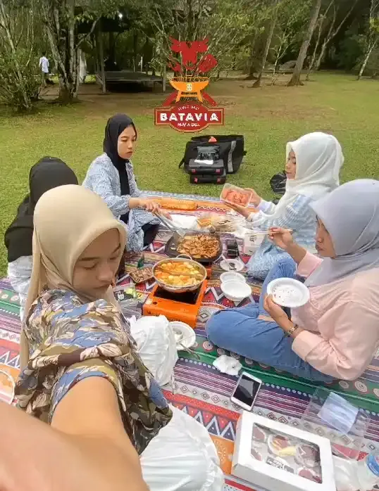 Keluarga piknik nge-grill di lapangan rumput